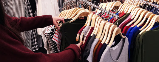 woman searching through a rack of clothes in a store reposted by Made for Freedom