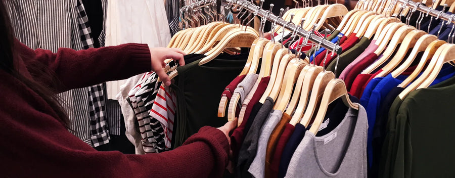 woman searching through a rack of clothes in a store reposted by Made for Freedom