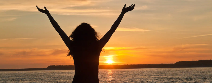 a silhouette of a woman against the sunset with her arms raised above her head reposted by Made for Freedom