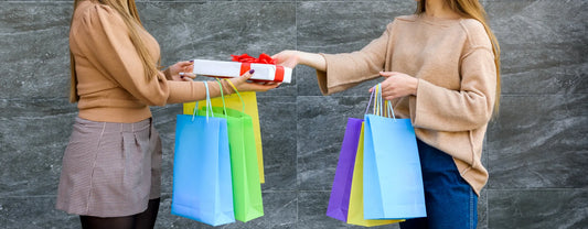 two women exchanging gifts while holding shopping bags reposted by Made for Freedom