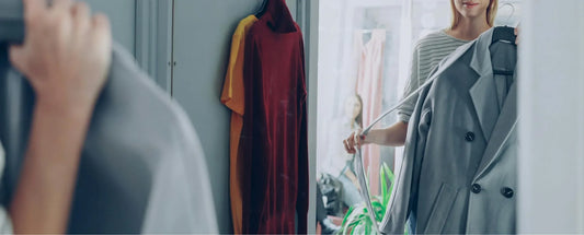woman holding a coat while looking at herself in the mirror reposted by Made for Freedom