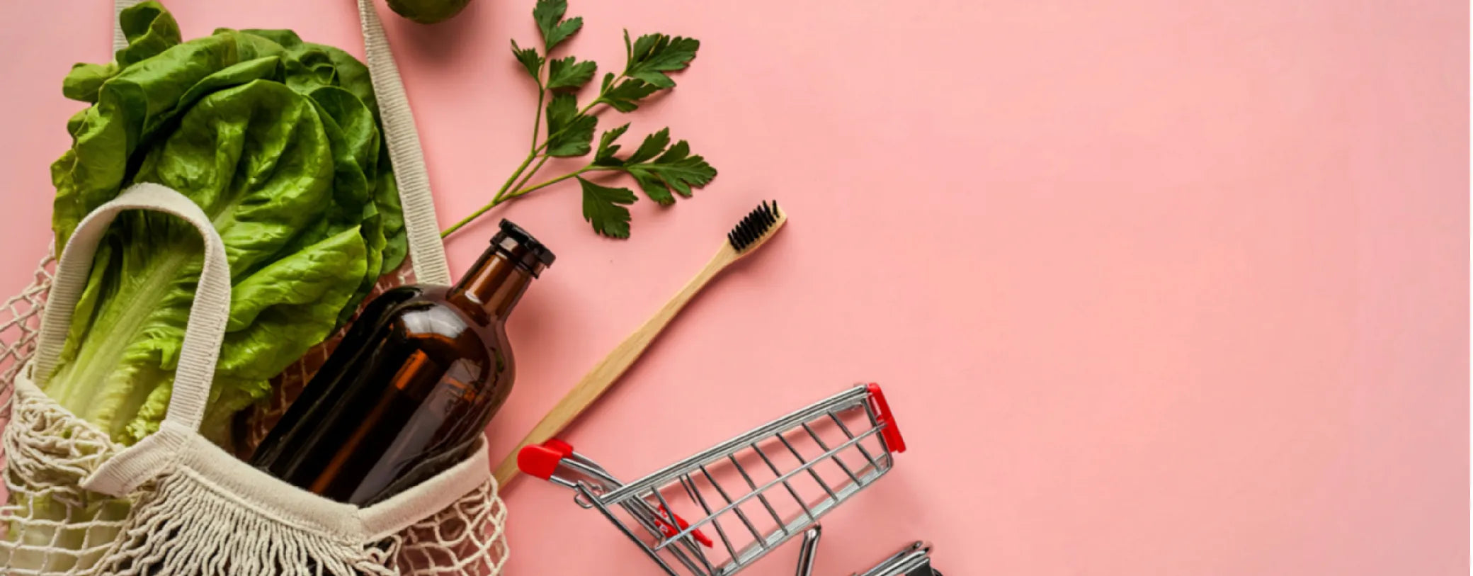 grocery items in a mesh shopping bag spilling out on a pink surface to symbolize sustainable shopping reposted by Made for Freedom