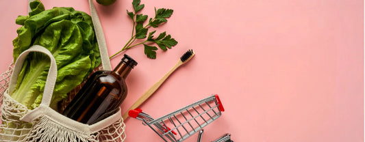 grocery items in a mesh shopping bag spilling out on a pink surface to symbolize sustainable shopping reposted by Made for Freedom