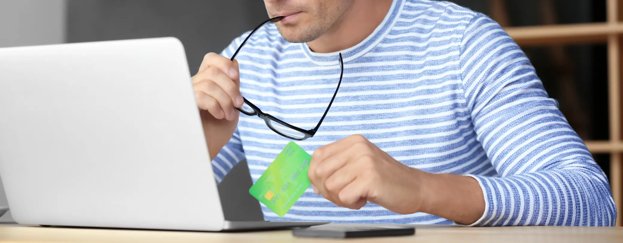 man looking at his computer while holding his credit card and deciding what to purchase reposted by Made for Freedom