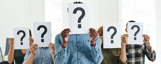 Diverse group of people holding question mark signs in front of their faces, symbolizing uncertainty, identity, or ethical decision-making.