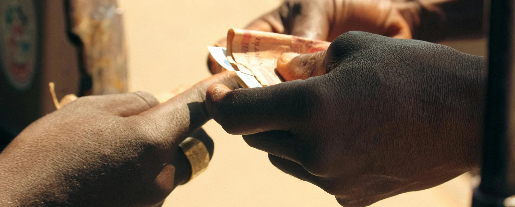 close-up of two people exchanging money by hand outdoors