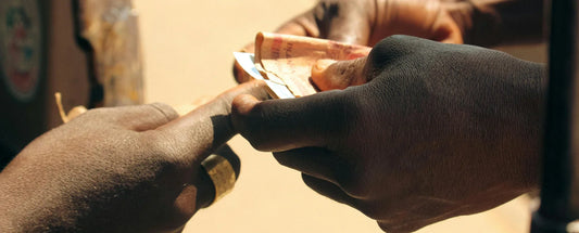 close-up of two people exchanging money by hand outdoors