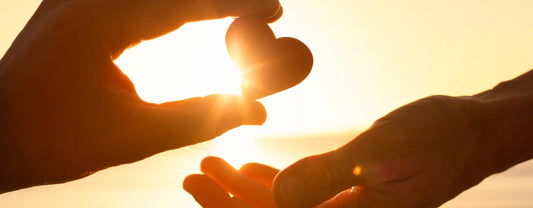 silhouette of hands exchanging a heart shaped object in front of the sunset reposted by Made for Freedom