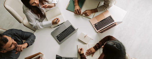 colleagues gathered around a desk on their computers reposted by Made for Freedom
