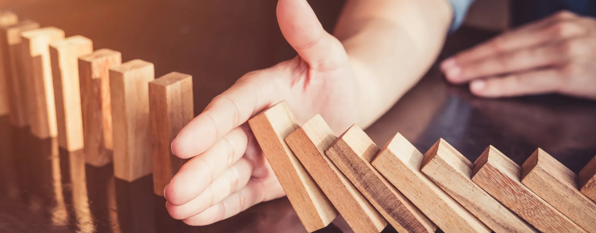 hand preventing a row of dominoes from falling onto each other reposted by Made for Freedom