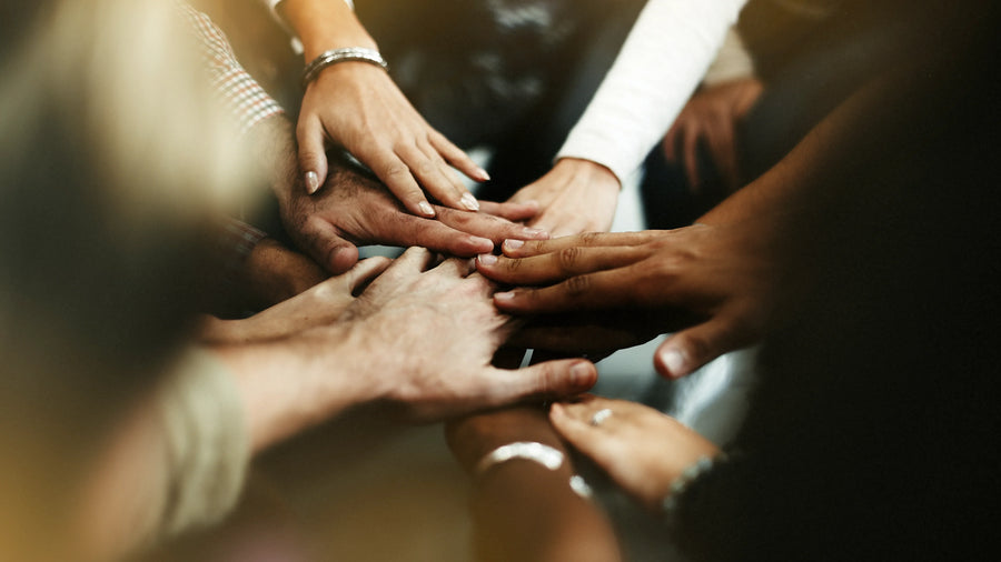 Diverse group of people joining hands together in a circle to symbolize unity, support, and community action.