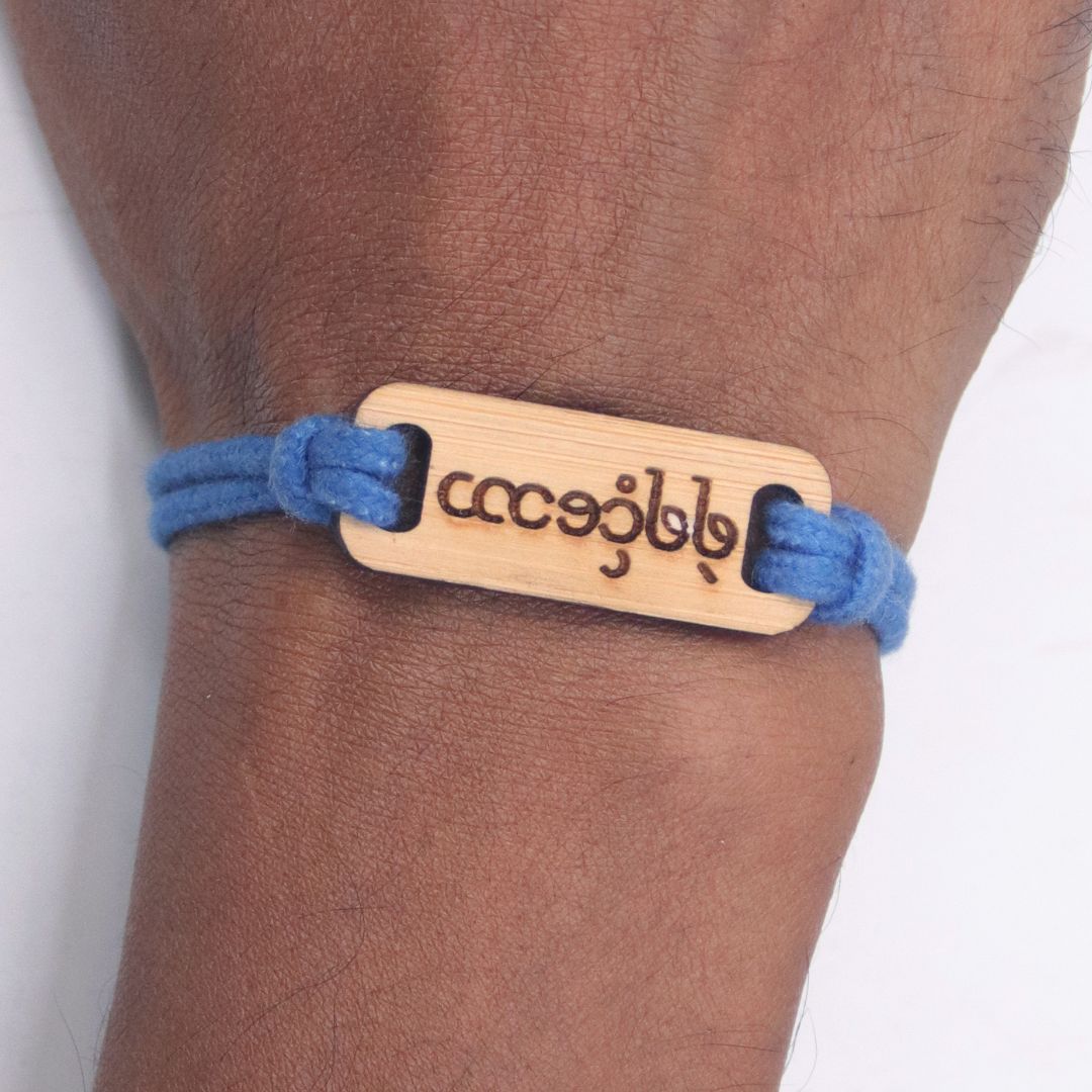 Bracelet with wooden tag and blue cord on wrist
